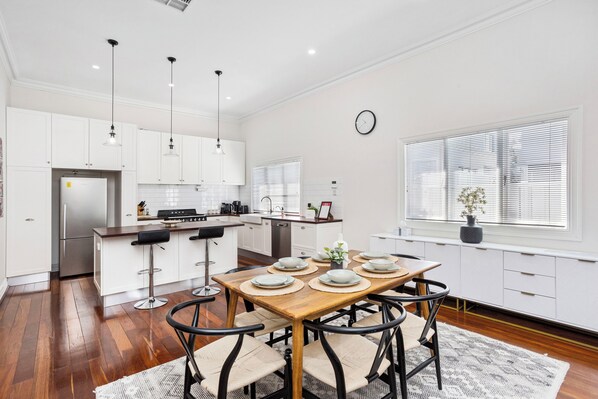 Dine in style at our inviting wooden table and chairs, adjacent to the open kitchen and a large window that floods the space with natural light.