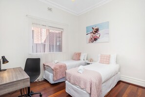 Enjoy in a bright bedroom with two twin beds, a desk, and a large window.