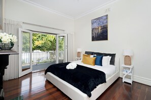 Escape to our spacious bedroom, featuring a comfortable bed adorned with yellow and blue pillows, and a large glass doors lead to a patio.