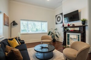 Funky living room, couch two separate modern arm chairs, TV.