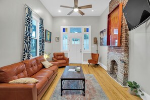 Relax in style! This vibrant living room combines modern comfort with historic charm, featuring exposed brick, eclectic artwork, and cozy leather seating. Perfect for unwinding after a day exploring New Orleans, this space is a true blend of local character and contemporary flair.