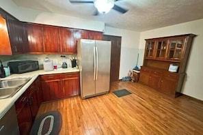 Fully stocked kitchen with Ice maker, hutch, microwave and double door stainless steel refrigerator.