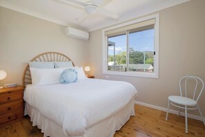 The primary bedroom highlights a plush queen-sized bed with air-conditioning and a ceiling fan to keep things cool.
