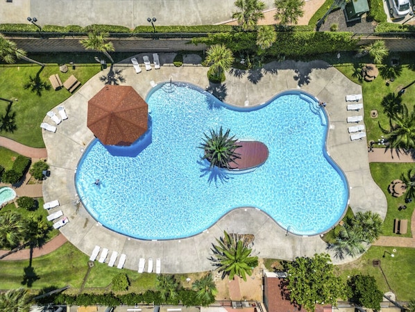 Enjoy this tropical communal pool with loungers.