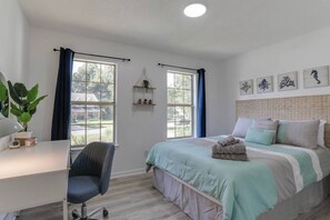 Bright and inviting, the second bedroom features a cozy queen bed, a convenient desk, and large windows that fill the space with natural sunlight.