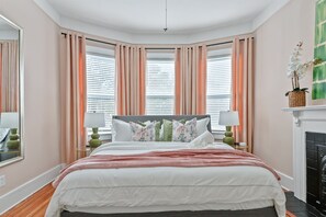The Street View Suite offers a luxurious king bed with extra pillows and a cozy blanket, plus a smart TV and dresser, making it the perfect spot to relax and enjoy a peaceful retreat.