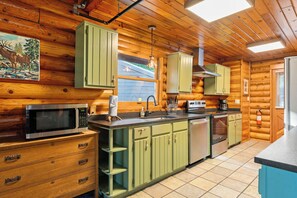 - Cook up your favorites in this charming kitchen with vintage green cabinets & modern appliances
- Rustic log walls & warm lighting blend function with timeless style
- Whether it's breakfast for two or dinner for a dozen, you've got space to create