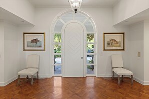 The grand foyer has a beautiful wood panel door, and parquet floors. 