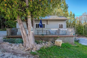 The Hawaii cabin features a cozy front deck with seating and a large umbrella, perfect for outdoor relaxation amidst the trees.