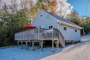 The Hukilau cabin features an elevated deck surrounded by lush trees, offering a peaceful and scenic retreat.