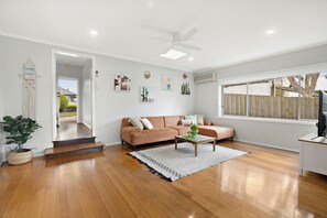 Large living room with smart TV, large couch, floor boards with heating and cooling