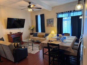 Living room, apartment # 3 : 2 pull out Sofas ( full size) , ceiling, fan, TV, dining area, AC on window.