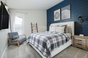 The first of two bedrooms, offering a plush queen bed & Smart TV