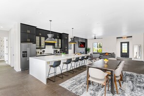 Fully Equipped Kitchen featuring stainless-steel appliances, a kitchen island with seating for 5 guests, a dining table with seating for 8 guests and a pool table.