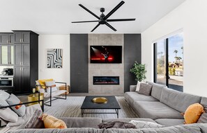 Large living space featuring an electric fireplace, a Smart TV and designer furnishings.