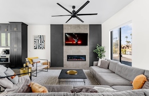 Large living space featuring an electric fireplace, a Smart TV and designer furnishings.