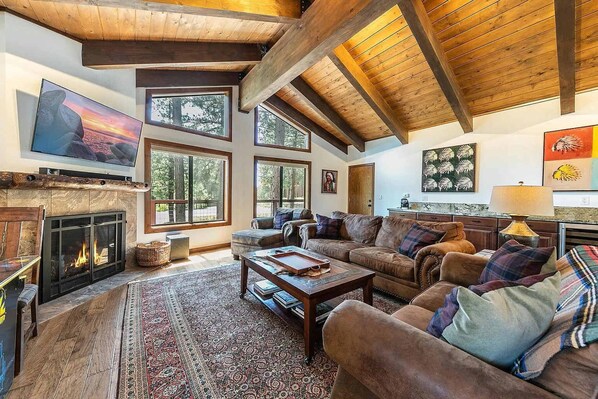 Living Room: Plush furnishings, 55” Smart TV, gas fireplace, wet bar with wine cooler and sink, arcade Pac-Man game, soaring windows 
