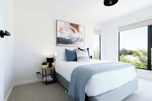 Relax in the plush bed with soft, cozy pillows that make it hard to get up. The spacious bedroom features beautiful artwork and large windows that let in plenty of natural light, offering a peaceful retreat.