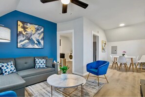 A vibrant living room featuring a cozy gray sectional sofa, accented by bold blue and white decor, perfect for relaxation and entertainment.