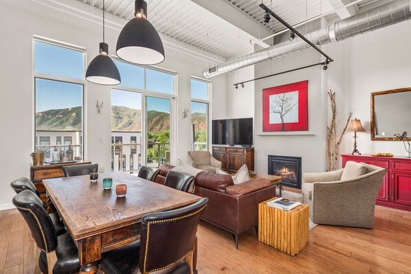 Open-concept kitchen, living, dining area with floor-to-ceiling windows of the hillside.