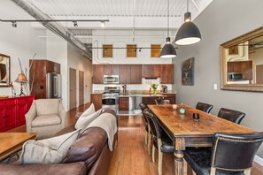 Open-concept kitchen, living, dining area with floor-to-ceiling windows of the hillside.
