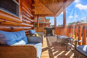 Porch includes comfortable outdoor seating and a propane grill.
