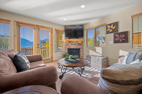 Experience the cozy living room, outfitted with plush seating, a fireplace, a smart TV, and patio doors that frame the breathtaking mountain vistas.