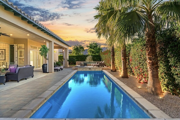 Luxurious backyard with a sparkling pool and cozy outdoor seating at sunset.
