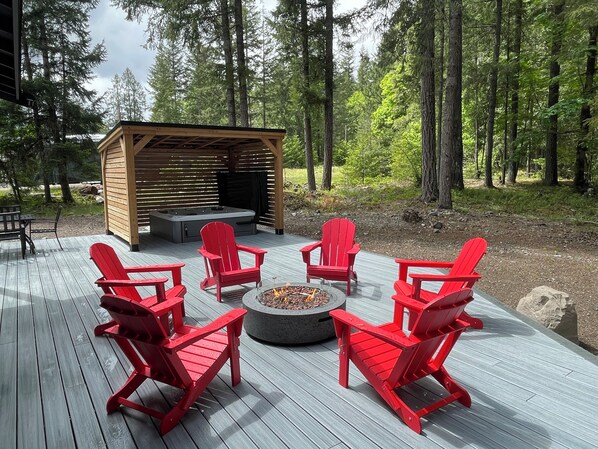 7-person hot tub with covered privacy gazebo and gas fire table with adirondack chairs situated on a spacious Trex deck.