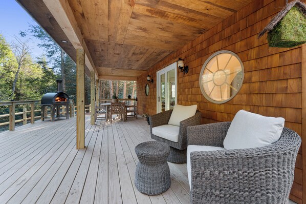 Back deck with comfortable chairs, pizza oven and hot tub