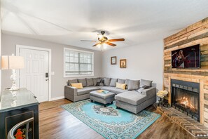 Stylish open-concept living area with designer furnishings, smart TV, and fireplace (for decoration only).