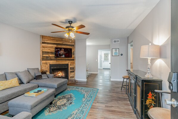 Stylish open-concept living area with designer furnishings, smart TV, and fireplace (for decoration only).