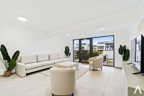 Spacious Lounge with a View – A serene shared living area with a large window overlooking the vibrant surroundings.