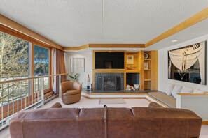 Living area featuring a wood burning fireplace with a mounted TV, and a queen sleeper sofa.