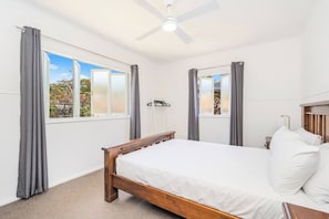 The first bedroom is set with a queen bed, ceiling fan, side tables and reading lights.