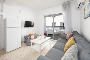 Open-plan living room with sofa, kitchen, A/C, WiFi internet, and satellite TV
