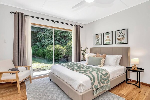 The spacious primary bedroom features a queen-size bed with glass sliding doors leading to the yard.