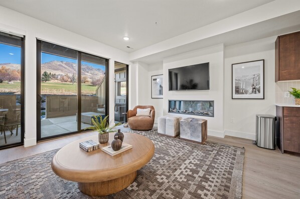 The living room has a large smart TV, electric fireplace, amazing views, and direct access to the deck.