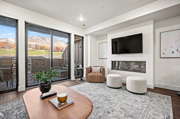 The living room has a large smart TV, electric fireplace, amazing views, and direct access to the deck.