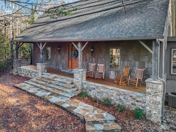 A cozy exterior of a charming, rustic-style house surrounded by trees.