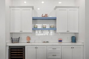 A stylish kitchen with crisp white cabinets, a sleek wine fridge, and just the right touch of color for a cheerful, inviting feel!