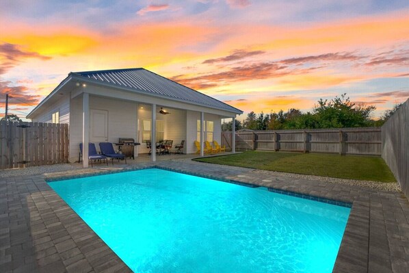 A private backyard with a sparkling pool at sunset, featuring cozy seating and a grilling area, perfect for evening relaxation and gatherings!
