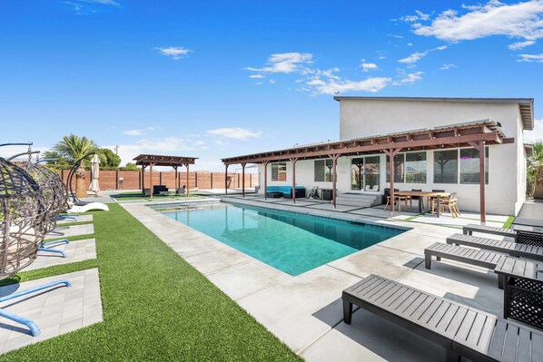 Relax in the stunning backyard featuring a pool, spa, putting green, pickleball court, and corn hole