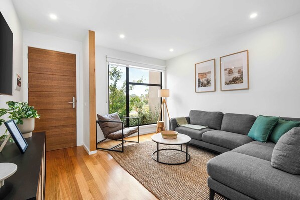 Lounge room with flat screen TV, arm chair and ample seating.