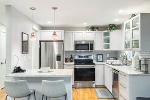 A clean, modern kitchen with a counter and stools, perfect for casual gatherings or quick meals.