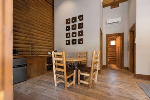 The Double Queen Suite's cozy dining area features handcrafted log furniture, perfect for meals or games in a charming mountain setting.