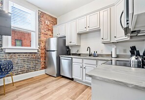 Stainless steel appliances and exposed brick accents bring together urban charm and practical convenience in this inviting kitchen.