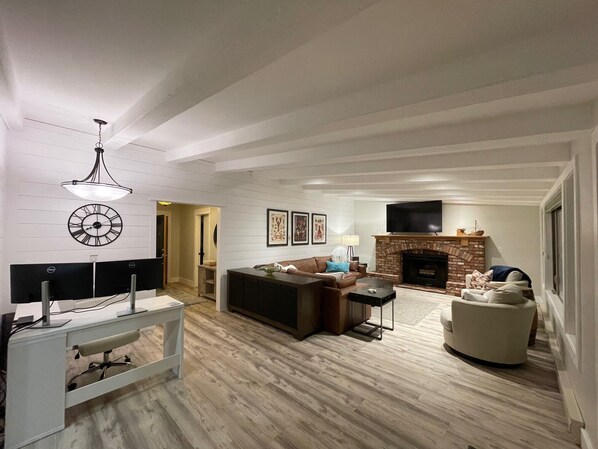 Living room with lots of seating, 70" smart TV, wood burning fireplace, office