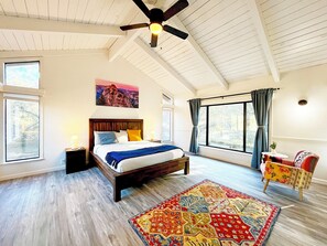 Wake up to forest views and natural light in this vaulted, cozy-modern bedroom.