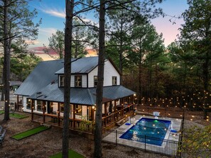 A serene pool lit with warm string lights, surrounded by nature.